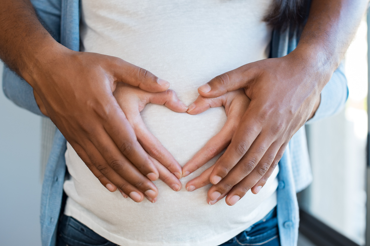 Pregnant Couple Making Heart Hand Gestures on Belly